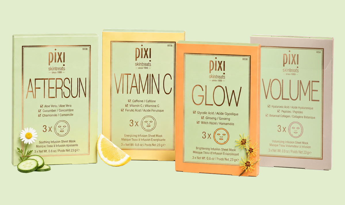 Four Pixi skincare sheet mask packets arranged side by side on a pale green background, with decorative food props including a daisy, cucumber slices, and a lemon wedge. The packets are labeled Aftersun, Vitamin C, Glow, and Volume. View 1