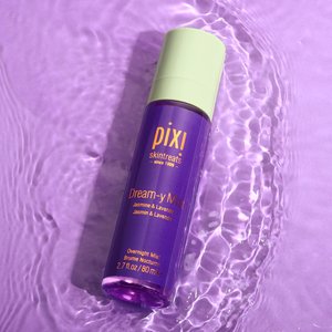 A bottle of PIXI Dream-y Mist sleep spray on a purple background with water ripples around it, indicating movement and freshness.